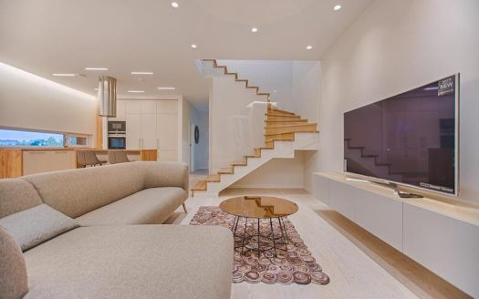 A modern living room with stairs and a tv.