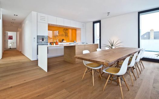 A white kitchen with wooden floors and a dining table.